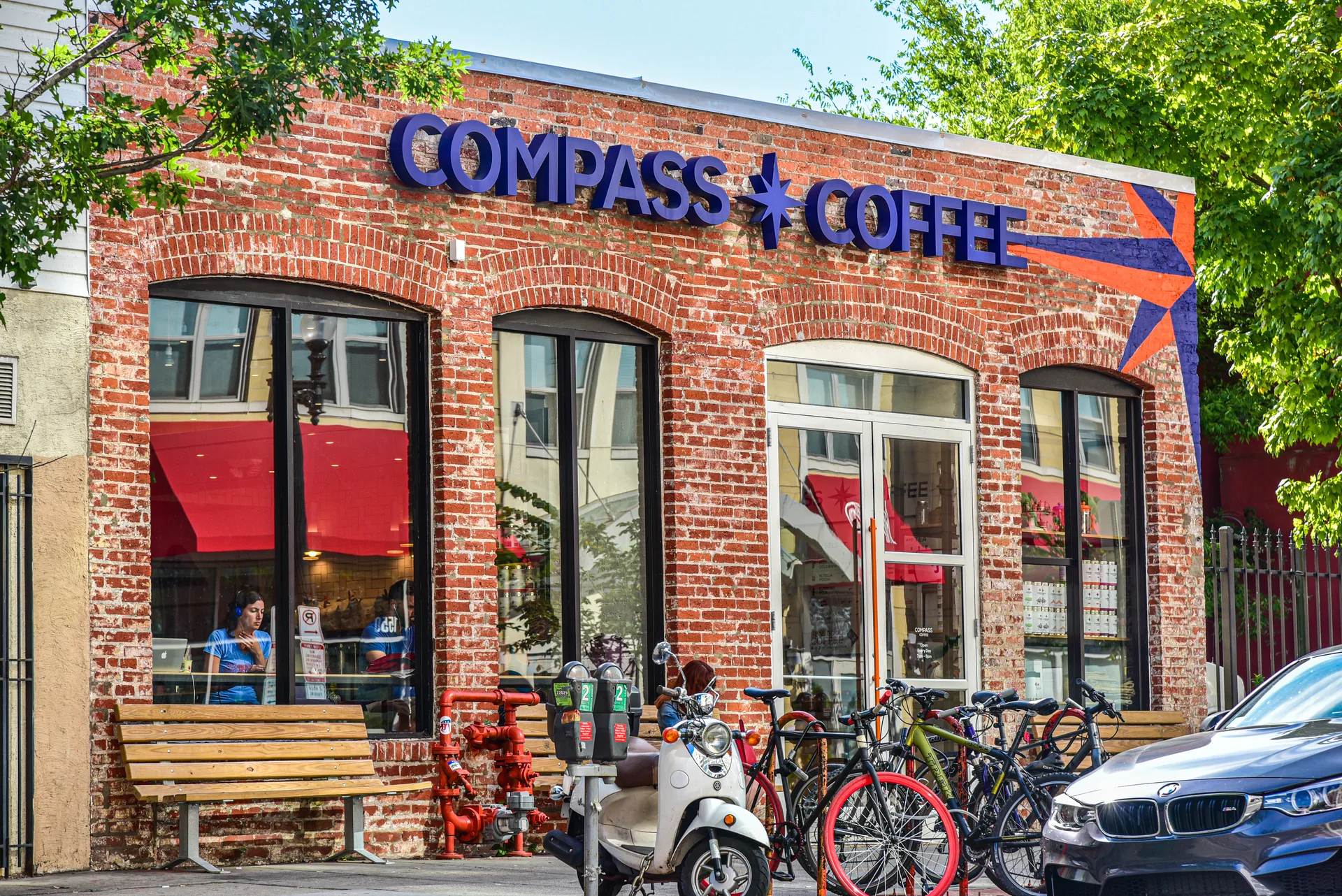 Brick Compass Coffee storefront with bicycles and a scooter outside
