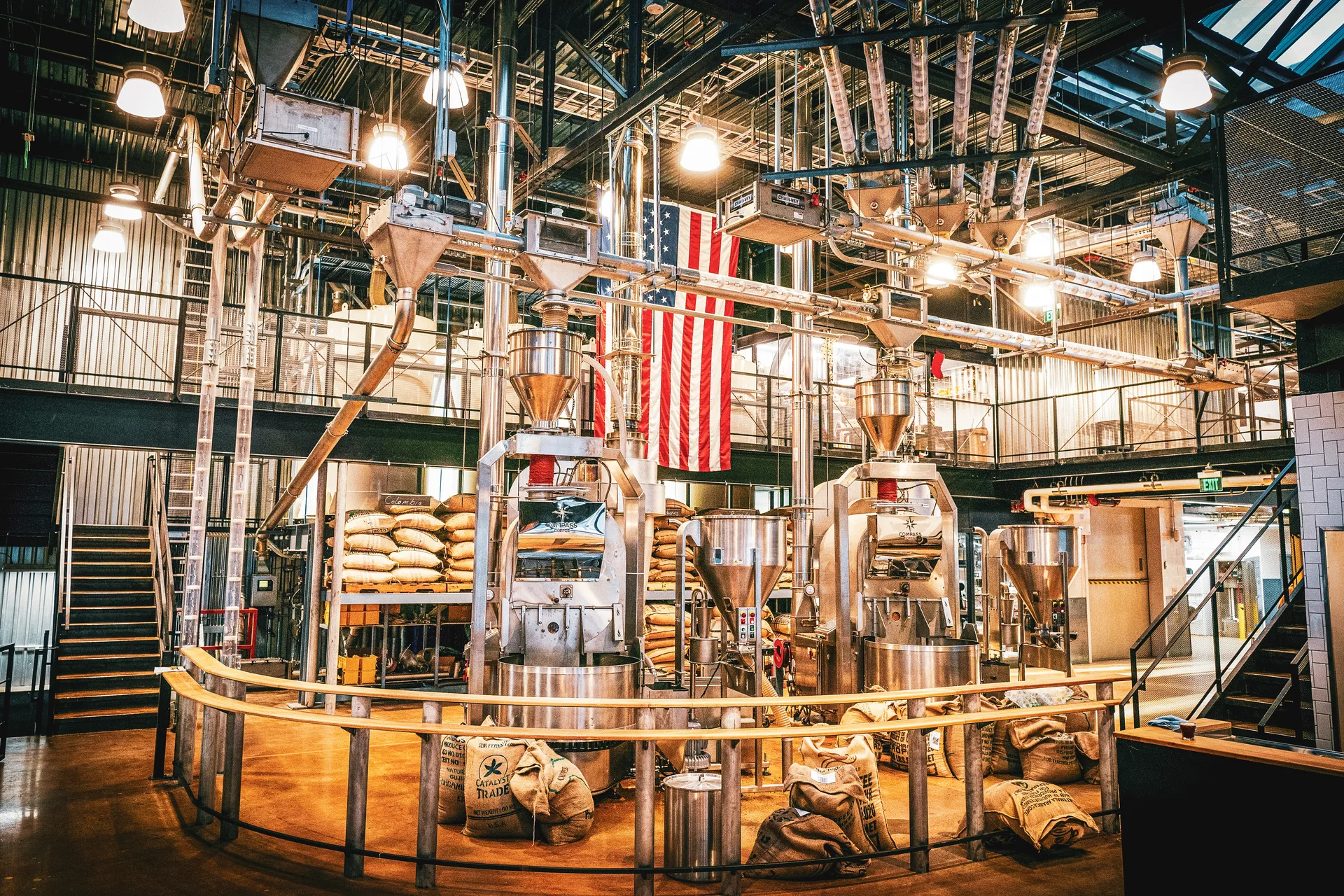 Coffee roasting machines and sacks of beans beneath an American flag