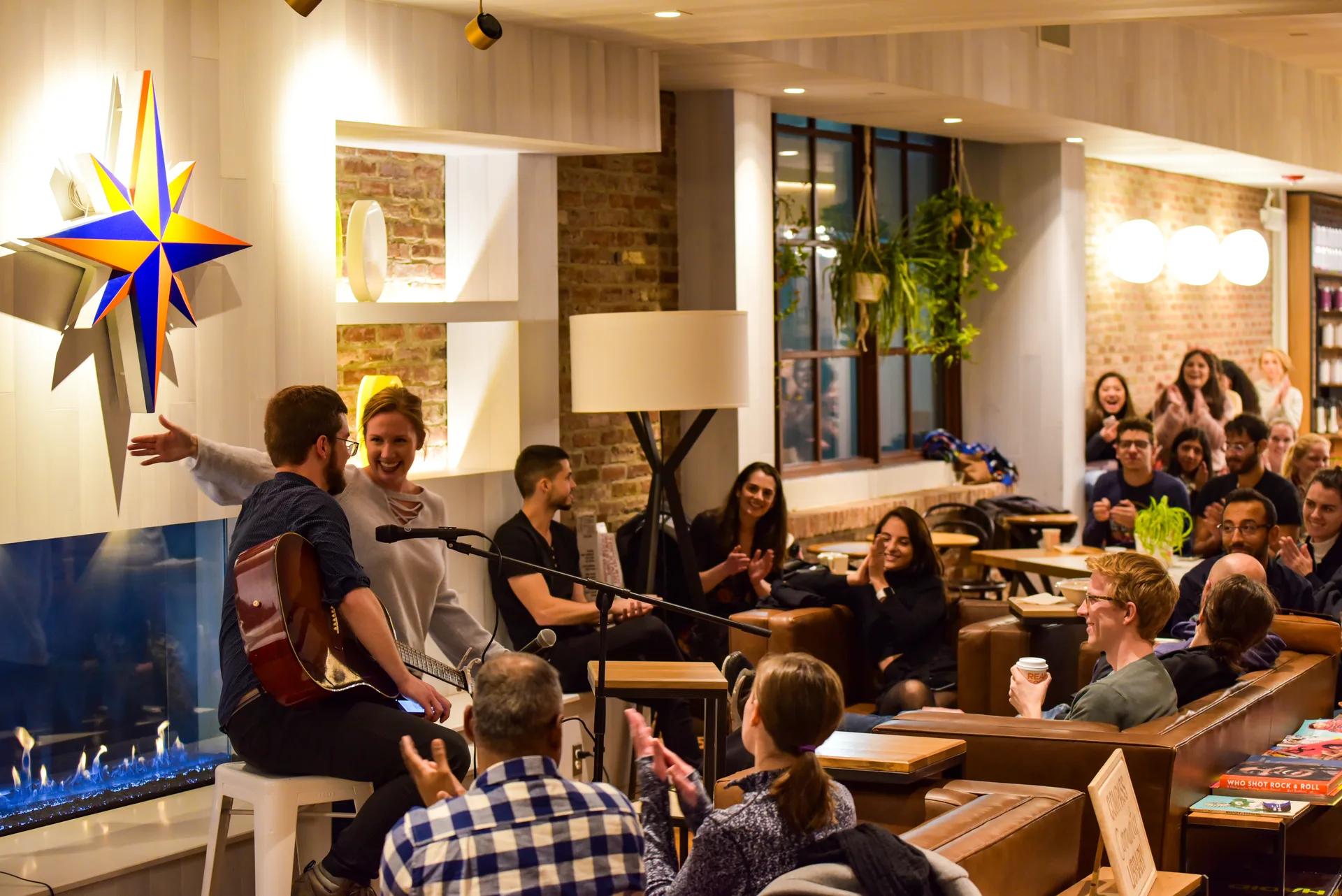 An audience gathered around a guitarist inside a cafe