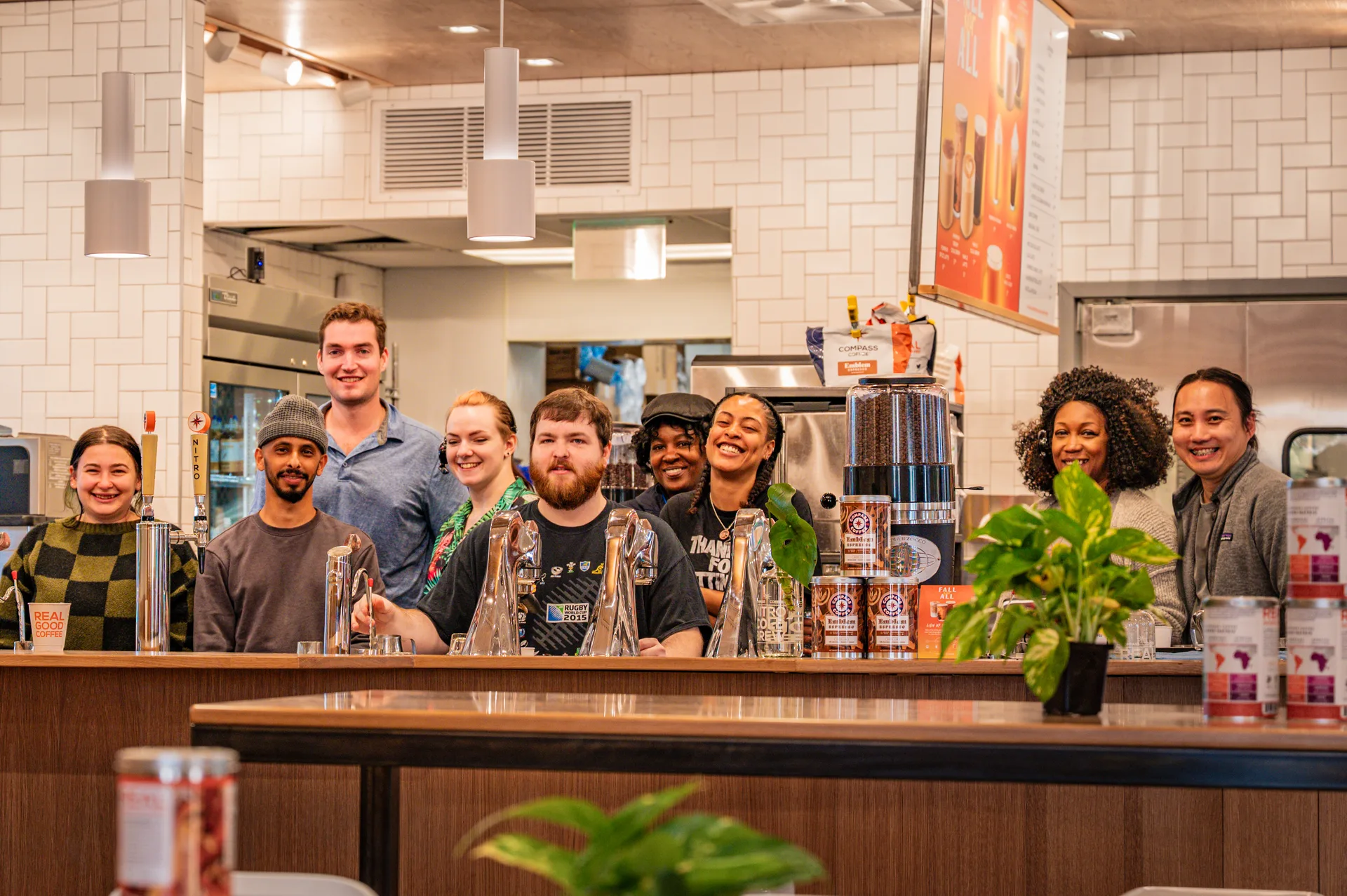 A group posing behind the Compass Coffee cafe counter