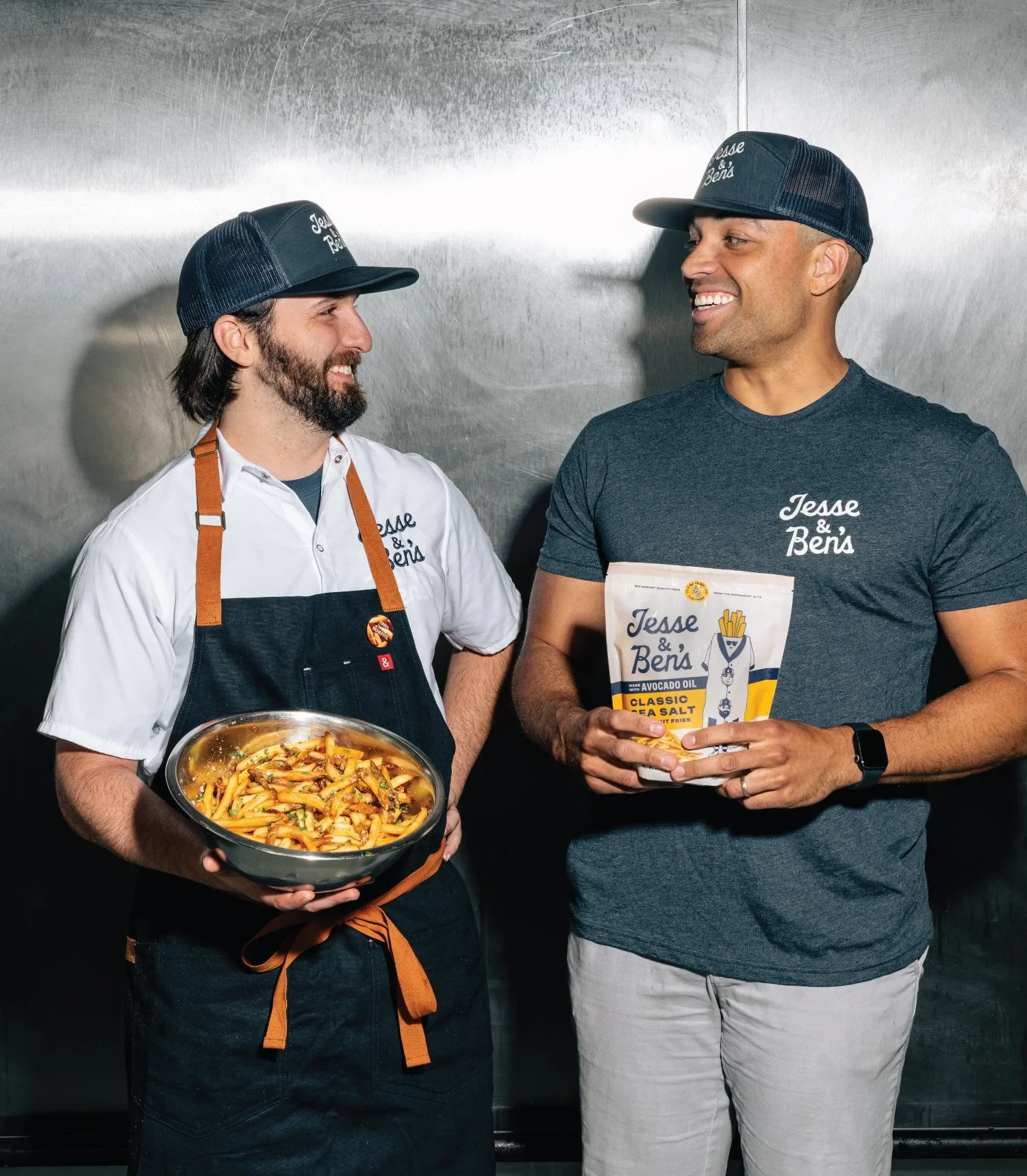 Two people holding a skillet of fries and a Jesse & Ben’s fries bag