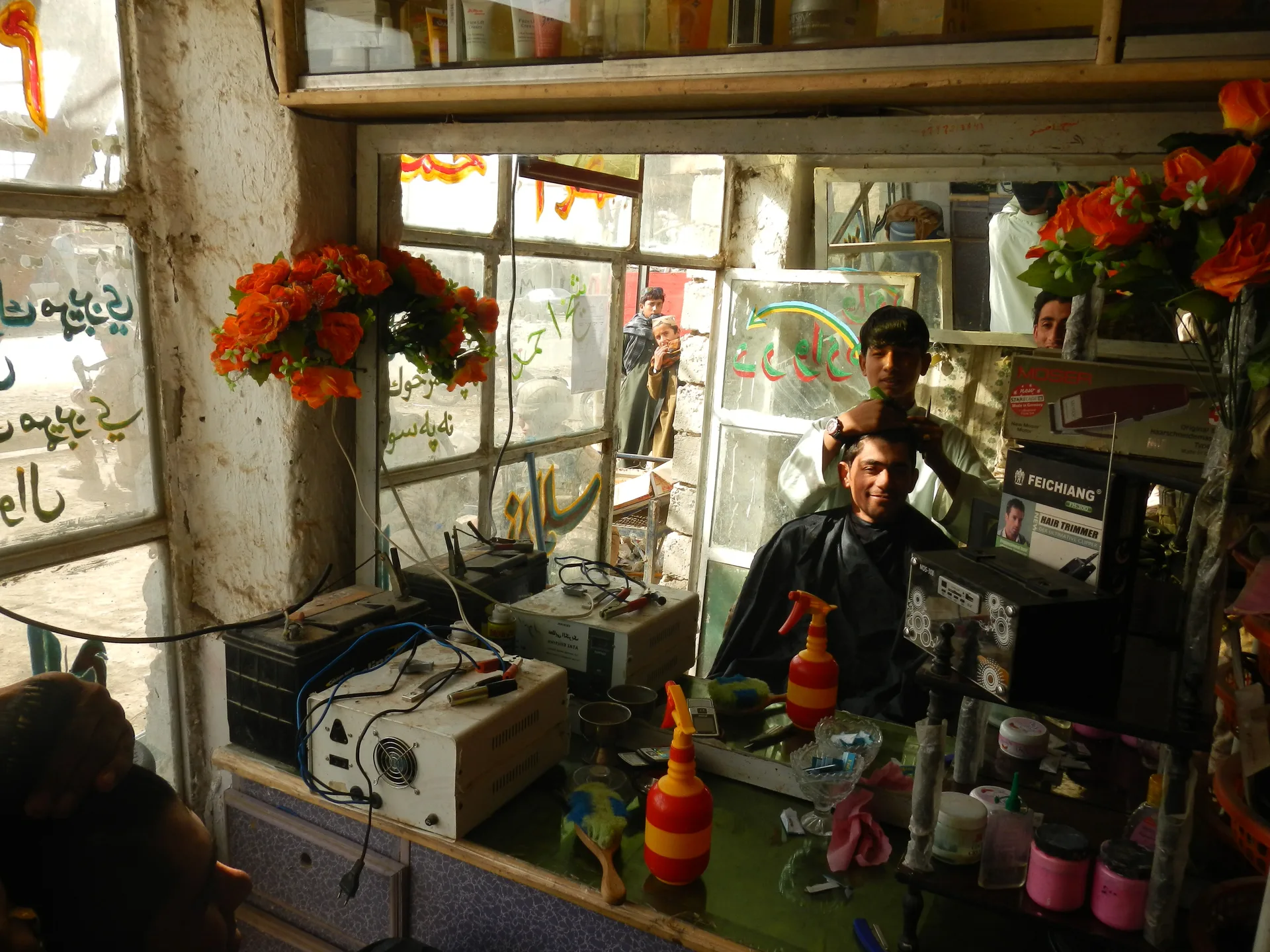 A barber cutting a man's hair in a sunlit shop lined with mirrors
