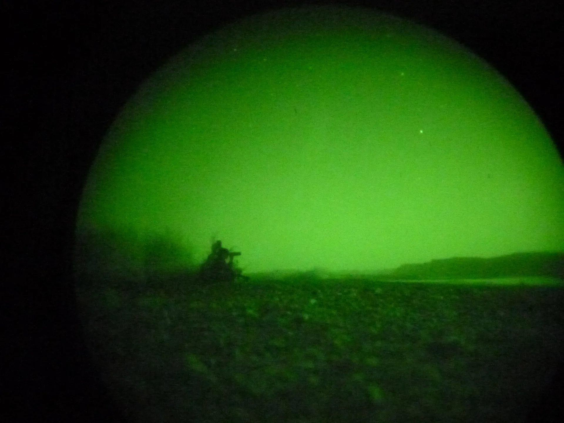 A silhouetted figure seen through green night-vision optics