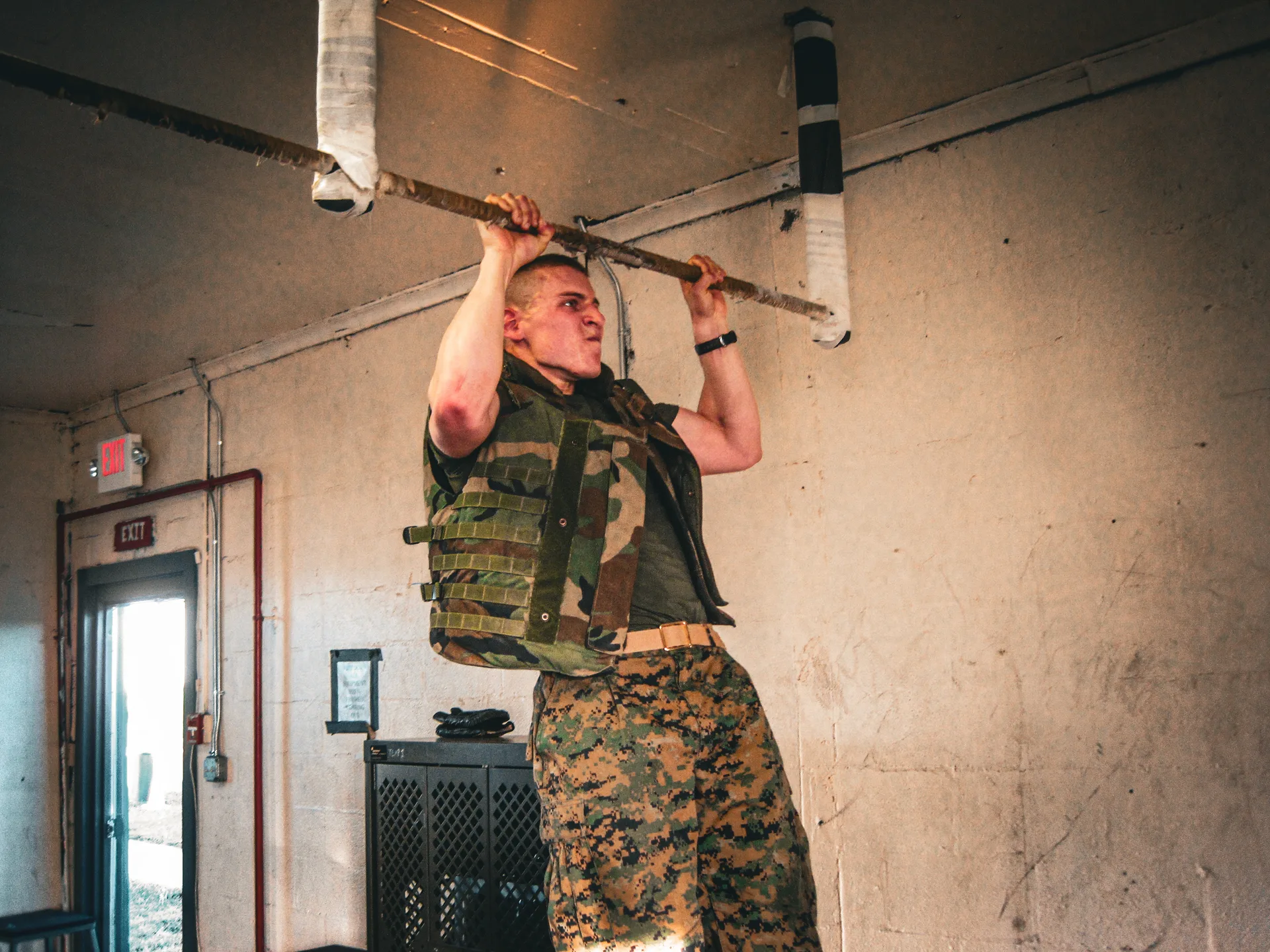 A Marine performing a pull-up while wearing a weighted vest