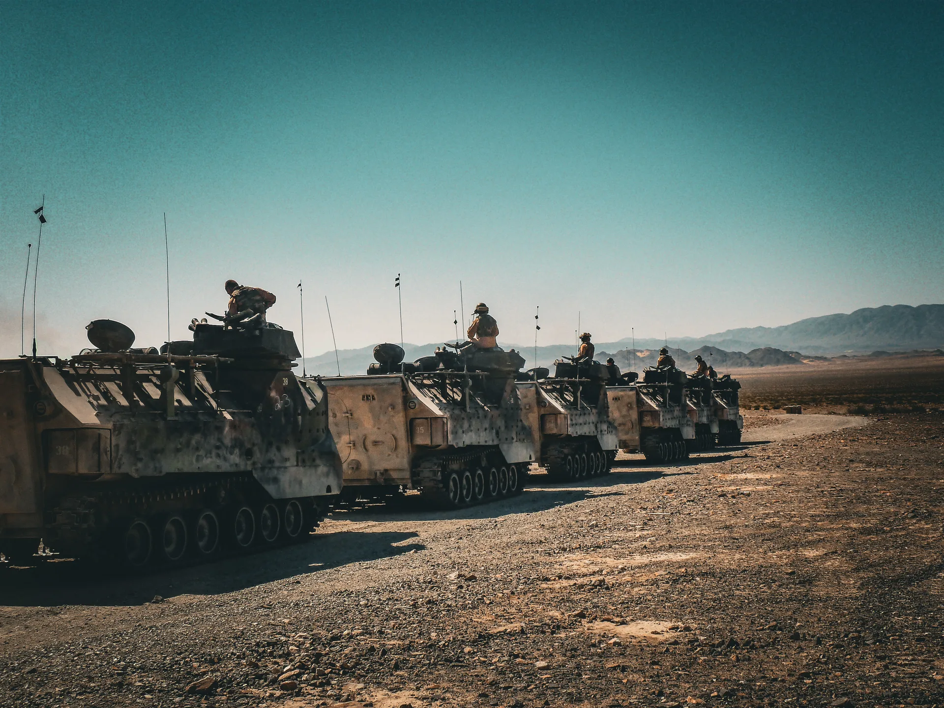 A line of tracked armored vehicles on a desert training ground