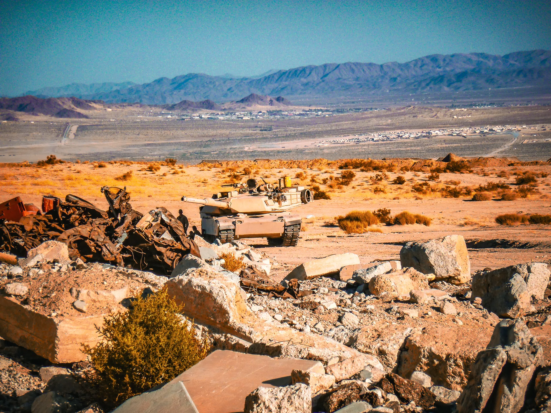 A tank on rocky desert terrain with mountains in the distance