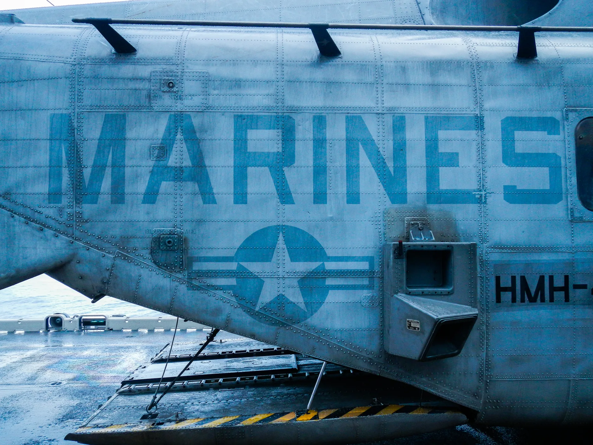 Close view of a helicopter marked Marines on a wet ship deck